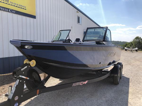 Slide: The Image of 2024 Alumacraft Trophy 195 boat on trailer outside sales and service building. - 2