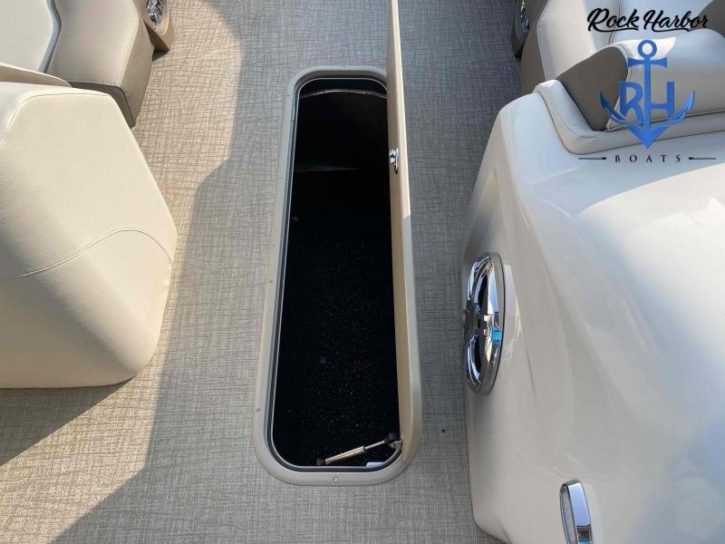 Slide: The Image of Open storage compartment on 2023 Avalon 2585 Catalina Cruise Funship boat, beige interior, Rock Harbor Boats logo. - 13