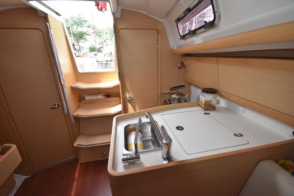 Slide: The Image of Interior of 2012 Beneteau First 30 sailboat with compact kitchen and wooden cabinetry. - 25