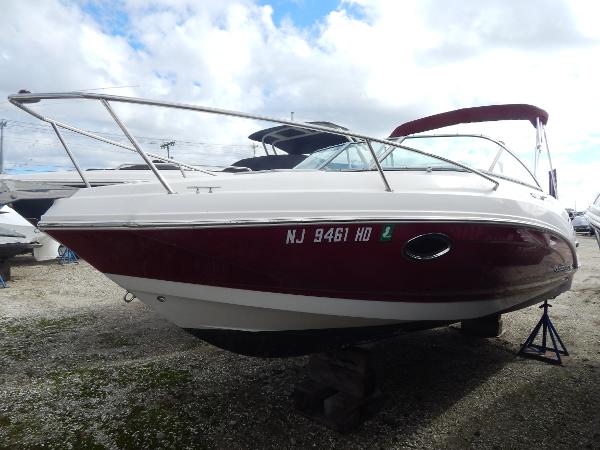 Slide: The Image of 2013 Chaparral 225 SSi boat with red and white hull, docked on land. - 1