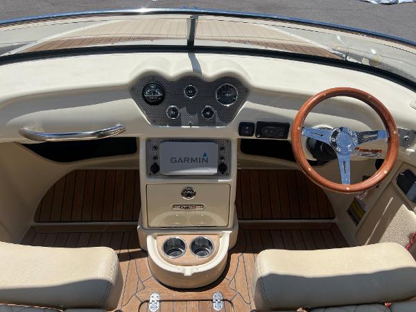 Slide: The Image of 2020 Chris-Craft Capri 21 boat dashboard with Garmin navigation, wooden steering wheel, and beige interior. - 12