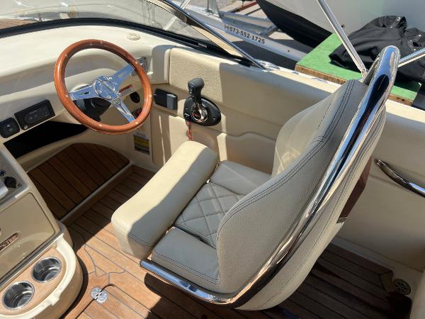 Slide: The Image of 2020 Chris-Craft Capri 21 boat cockpit with wooden steering wheel and beige leather seat. - 13