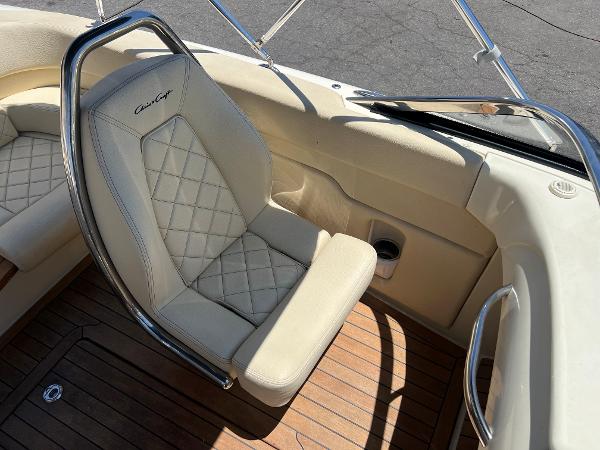 Slide: The Image of 2020 Chris-Craft Capri 21 boat interior with beige leather seating and wooden flooring. - 16