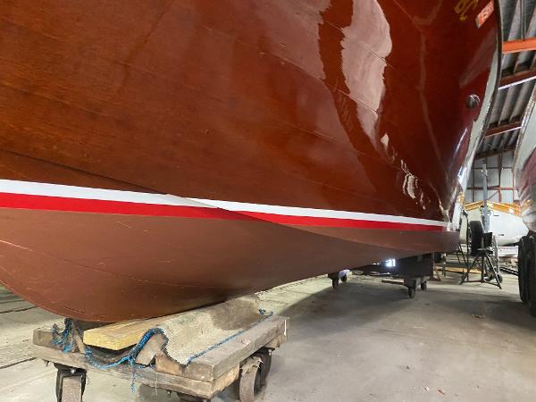 Slide: The Image of 1959 Chris-Craft Sportsman boat hull in storage, showcasing polished wood and red stripe. - 3