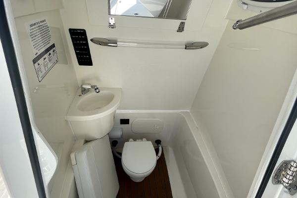 Slide: The Image of 2024 Cobia 262cc boat interior bathroom with sink, toilet, and mirror. - 18