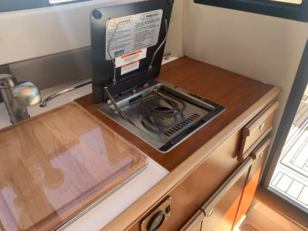 Slide: The Image of 2022 Cutwater C-24 Coupe kitchen area with stove and wooden countertop. - 15