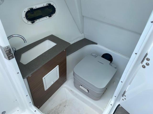 Slide: The Image of 2023 Four Winns H260 boat interior with sink and portable toilet. - 13