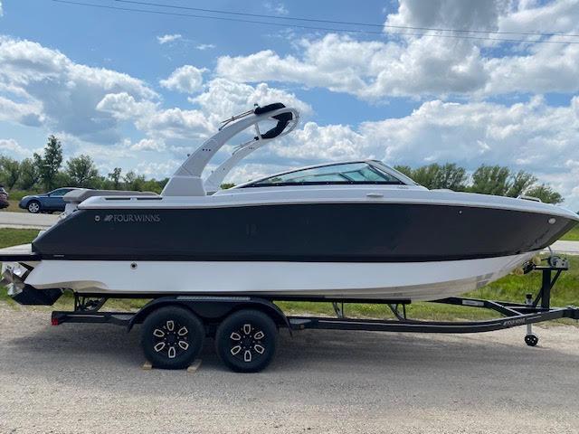Slide: The Image of 2023 Four Winns H260 boat on a trailer under a partly cloudy sky. - 7