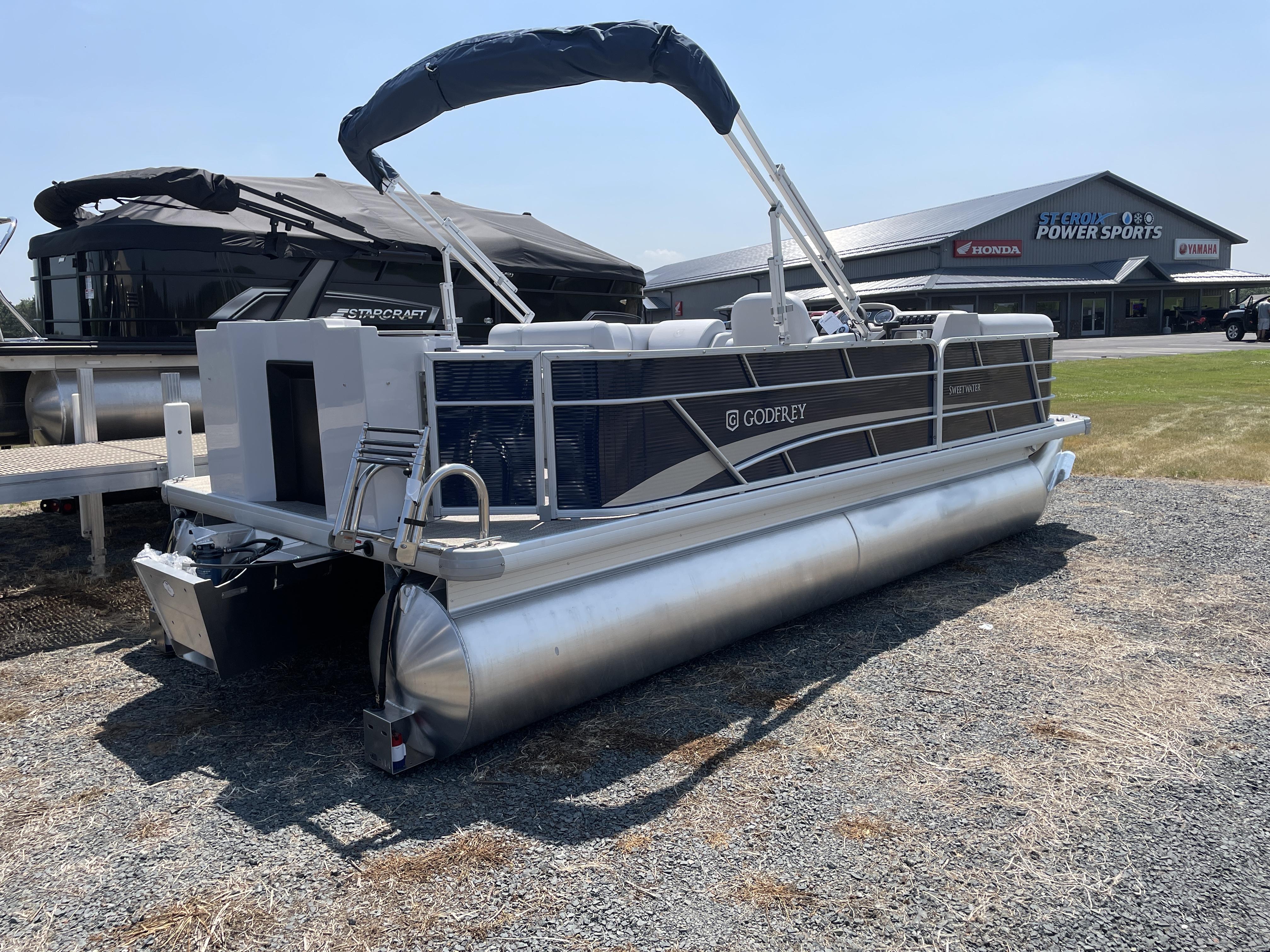 Slide: The Image of 2024 Godfrey SW2186FS pontoon boat displayed at a dealership. - 1