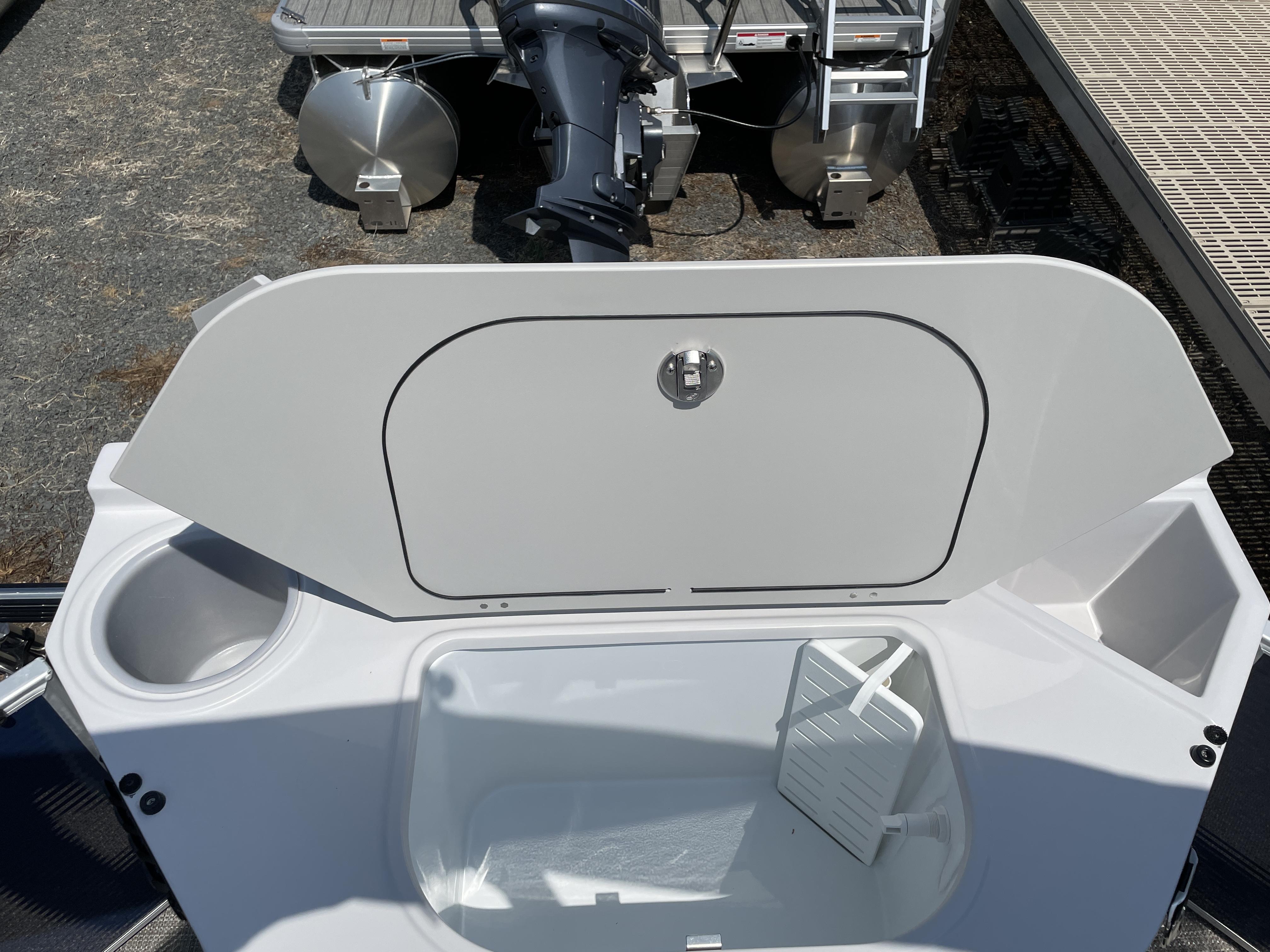 Slide: The Image of 2024 Godfrey SW2186FS boat storage compartment with open lid and cup holder. - 2