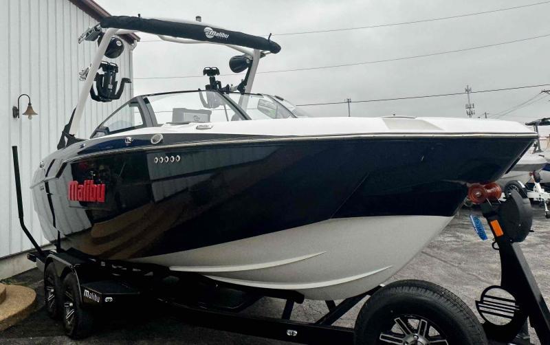 Slide: The Image of 2024 Malibu M220 boat on trailer, black and white design, parked outdoors. - 7
