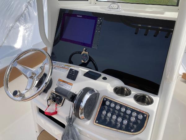 Slide: The Image of 2023 NauticStar 24 Legacy boat helm with steering wheel, control panel, and navigation screen. - 6