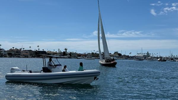 Slide: The Image of Northstar Orion 8 boat cruising near a sailboat in a scenic harbor, 2024 model. - 10