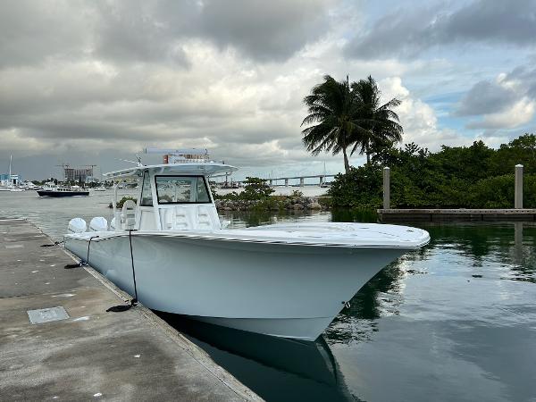 Slide: The Image of 2021 Onslow Bay 41 Tournament Edition boat docked by palm trees and cloudy sky. - 2