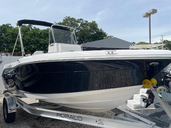Slide: The Image of 2023 Robalo R180 Center Console boat on trailer, sleek black and white design. - 1