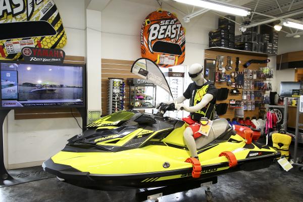 Slide: The Image of Showroom with 2023 Robalo R180 Center Console, mannequin on yellow jet ski, boating accessories displayed. - 49