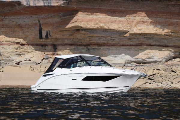 Slide: The Image of 2024 Sea Ray 32 Sundancer yacht cruising near rocky cliffs. - 2