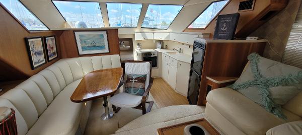 Slide: The Image of Interior of 2000 Silverton 392 Motor Yacht with white seating, dining table, and kitchen area. - 17
