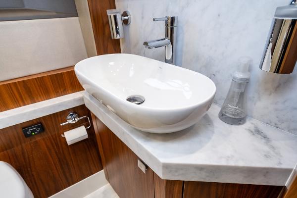 Slide: The Image of Modern bathroom sink in 2017 Sunseeker Manhattan 52 yacht, featuring marble countertop and wooden cabinetry. - 32