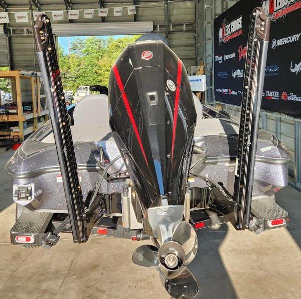 Slide: The Image of 2024 Triton 19 TrX Patriot boat in a garage, rear view with motor and propeller. - 2